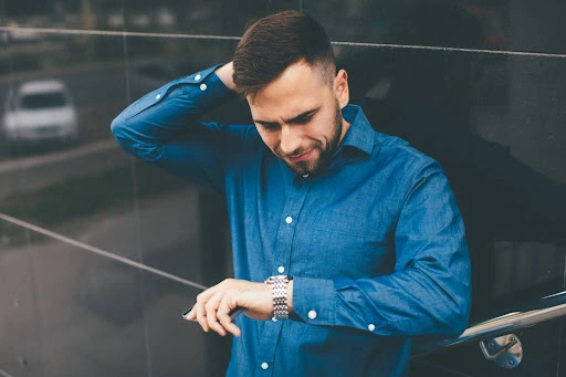 A man looking at his metal watch